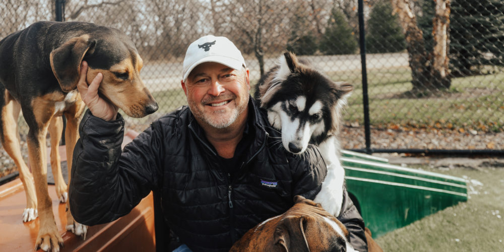 Man smiling with three dogs at his side